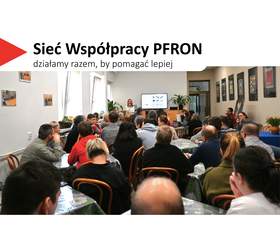 Sala wypełniona dorosłymi uczestnikami siedzącymi przy stołach, zwróconymi w stronę prowadzącego. Prelegent stoi z przodu z mikrofonem w dłoni, obok ekranu z wyświetloną prezentacją. W tle widać rośliny doniczkowe, drzwi oraz ściany ozdobione oprawionymi fotografiami. W lewym górnym rogu widnieje hasło „Sieć Współpracy PFRON – działamy razem, by pomagać lepiej”.