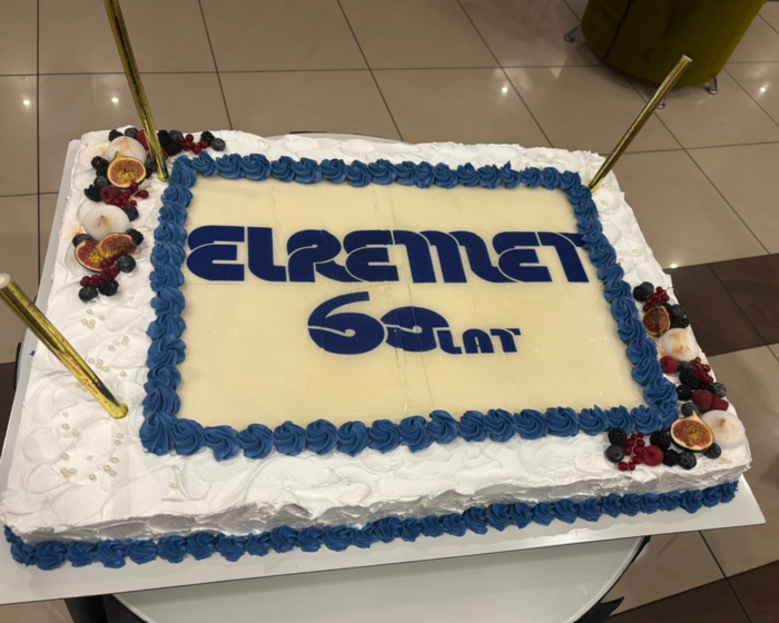 Pokaż zdjęcie: Zdjęcie prostokątnego tortu z racami po rogach, na środku logo ELREMET z napisem 60 lat.