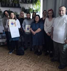 Pokaż zdjęcie: Do pamiątkowego zdjęcia pozuje grupa osób wyróżnionych w konkursie plastycznym. W rękach trzymają dyplomy.