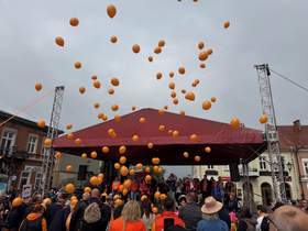 Przed sceną tłum, unoszące się w niebo pomarańczowe balony.