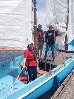 Pokaż zdjęcie: Zdjęcie trzech osób stojących w żaglówce.