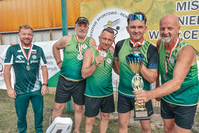 Pokaż zdjęcie: Kilku mężczyzn ubranych na sportowo prezentuje srerbne medale i okolicznościowy puchar