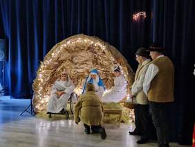 Zdjęcie wypełnia głównie podświetlona szopka z postaciami Maria, Józef, Aniołek, pastuszkowie