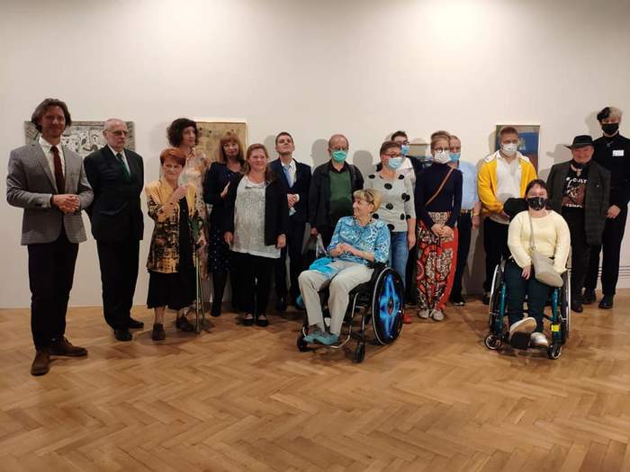 Pokaż zdjęcie: Na zdjęciu Laureaci konkursu oraz członkowie jury, przedstawiciele Fundacji Sztuki  Osób Niepełnosprawnych i Muzeum Narodowego. Wszyscy pozują na tle obrazów