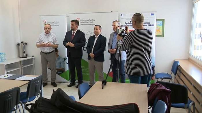 Pokaż zdjęcie: Na tle rollup z logo PFRON stoją osoby wystepujące na konferencji