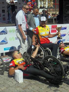 Pokaż zdjęcie: Pamiątkowe zjęcie pierwszej trójki zwycięzców w kategorii "wózkarzy hanbike" Mężczyzn. Za sportowcami stoji Dyrektor Oddziału Pomorskiego PFRON.