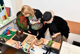 Plan zdjęcia stanowi sala w której na stołach ustawione są rzeźby. W centrum fotografii stoją członkowie komisji konkursowej.