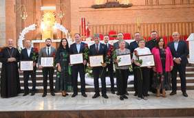 Pokaż zdjęcie: W kościele stoją osoby odznaczone, które otrzymały tytuł „Człowiek o godnym sercu”. Trzymają w doniach dyplomy oraz kwiaty. 