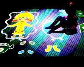 Pokaż zdjęcie: Dziecko korzysta z interaktywnego dywanu wyświetlającego różne wzory