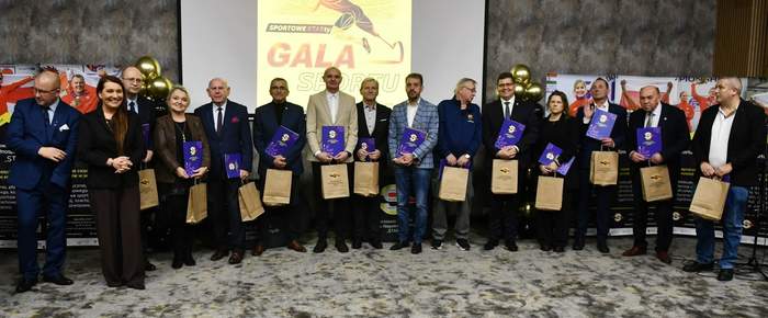 Pokaż zdjęcie: Uczestnicy Gali, ubrani na galowo, na tle Prezentacji z logo Start Gorzów