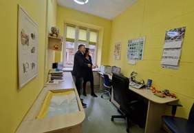 Pokaż zdjęcie: Kobieta i mężczyzna oglądają gabinet, w którym wykonuje się badanie słuchu