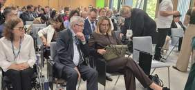 Pokaż zdjęcie: W rzędach siedzą uczestnicy konferencji „Dostępność dziś i jutro”. Na widowni znajdują się osoby w różnym wieku, w tym osoby z niepełnosprawnościami. 