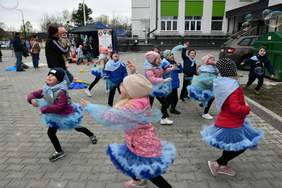 Pokaż zdjęcie: Zdjęcie na zewnątrz bawiących się dzieci. Dzieci mają niebieskie spódniczki.