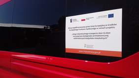 Pokaż zdjęcie: Zdjęcie zbliżonej naklejki z programu doo-to-door zamieszczonej na czerwonym busie 