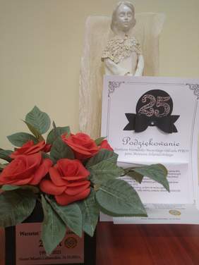 Pokaż zdjęcie: Bukiet sztucznych róż w pudełku oznakowanym tabliczką Warsztat Terapii Zajęciowej 1991-2021 Nowe Miasto Lubawskie 16.10.2021 r. Kartka z podziękowaniami dla Dyrektora Warmińsko-Mazurskiego Oddziału PFRON pana Mateusza Szkaradzińskiego. Gipsowy an