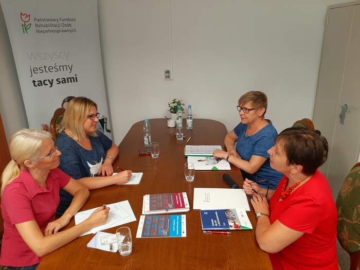 Pokaż zdjęcie: Cztery osoby siedzące przy stole