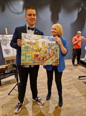 Pokaż zdjęcie: Mężczyzna i kobieta stoją trzymając obraz z pociągiem.