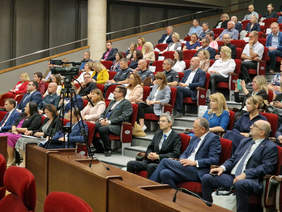 Sala konferencyjna, układ krzeseł jak kinie w rzędach wznoszących się coraz wyżej, kilkudziesięciu uczestników