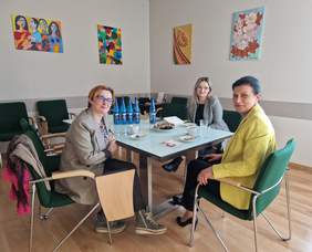 Pokaż zdjęcie: Trzy kobiety siedzą przy stole i rozmawiają