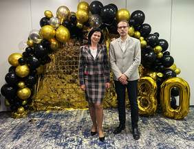 Pokaż zdjęcie: Kobieta i mężczyzna pozują do zdjęcia. W tle dekoracja z balonów i liczba 30.