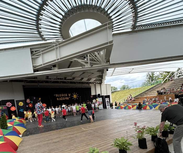 Pokaż zdjęcie: Amfiteatr, zdjęcie z widowni w kierunku sceny na której trwają występy przedszkolaków.