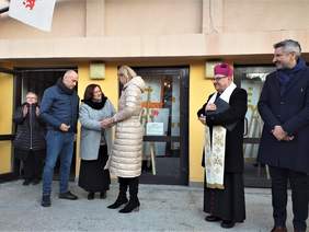 grupa dorosłych osób stoi przed wejściem do budynku