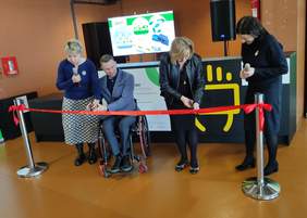 Pokaż zdjęcie: Trzy kobiety i mężczyzna na wózku przecinają wstęgę