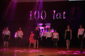 Pokaż zdjęcie: Na scenie stoją w rzędzie kobiety i mężczyźni, którzy rozpoczęli  taneczny krok