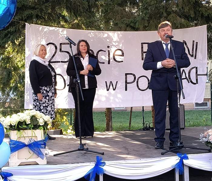 Pokaż zdjęcie: Przewodniczący na scenie wita gości - za nim napis 25-lecie PSONI