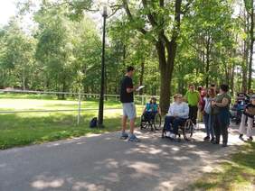 Pokaż zdjęcie: Grupa osób z niepełnosprawnością stojąca na drodze