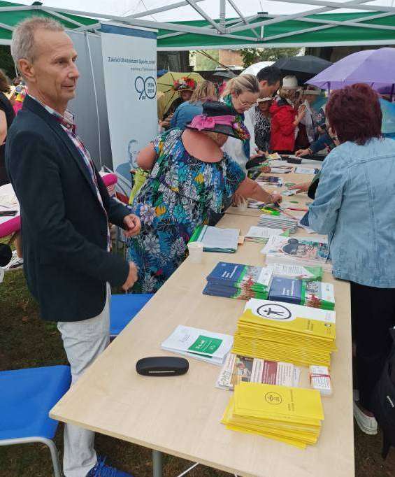 Pokaż zdjęcie: Stół z ulotkami PFRON i odwiedzający stoisko