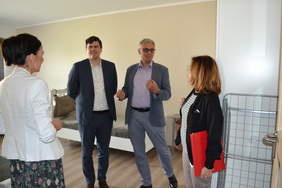 Pokaż zdjęcie: Dwie kobiety i dwóch mężczyzn są w mieszkaniu treningowym, za nimi łóżko