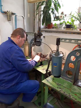 Pokaż zdjęcie: Monter wiązek  w trakcie pracy, na stoliku stoi specjalistyczna maszyna