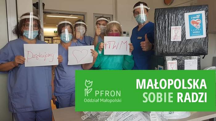 Pokaż zdjęcie: PTWM dziękuje za wsparcie - na zdjęciu pracownicy w maseczkach, przyłbicach w rękach trzymają kartki z podziękowaniami