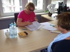 Pracownik Kujawsko-Pomorskiego Oddziału PFRON - Beata Celebucka i Dyrektor (tyłem) Oddziału - Aleksandra Gierej - podczas podpisywania umowy