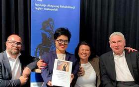 Dwie kobiety i dwóch mężczyzn pozują do zdjęcia. Jedna z kobiet to Laureatka konkursu, w dłoniach trzyma dyplom.