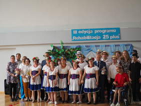 zdjęcie grupowe kilkunastu osób kobiet i mężczyzn, w tym w strojach ludowych, stoją, uśmiechaja się, pozują do zdjęcia