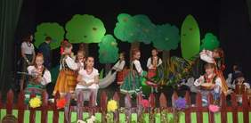 Pokaż zdjęcie: na scenie grupa dzieci ubrane w kolorowe ludowe stroje z Podlasia