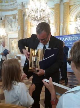 Pokaż zdjęcie: Mężczyzna trzymający w ręku statuetkę