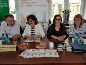 mężczyzna i 3 kobiety, siedzą za stołem