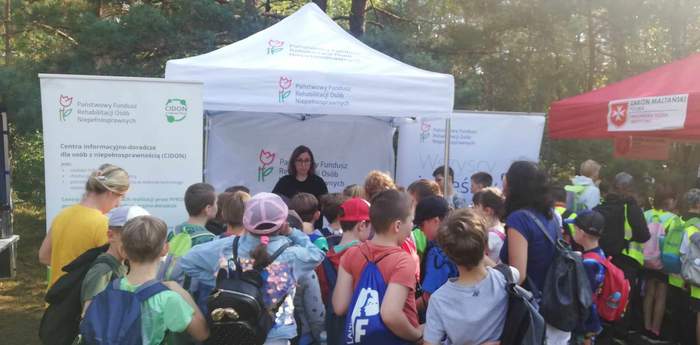 Grupa dzieci stoi przed punktem informacyjnym Kujawsko-Pomorskiego Oddziału PFRON