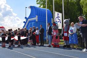 Pokaż zdjęcie: Na stadionie stoją osoby zaproszone na imprezę integracyjną "Spotkanie Przyjaciół". Są sportowcy, reprezentanci różnych instytucji oraz przedstawiciele lokalnych władz. 