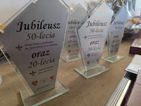 Pokaż zdjęcie: Na stole ustawione są statuetki z napisem z okazji Jubileuszu 50-lecia DPS w Brańsku oraz 20-lecia nadania mu imienia Świętego Jana Pawła II.