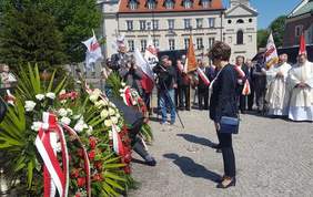 Złożenie kwiatów przed pomnikiem. Na pierwszym planie stojąca Marlena Maląg Prezes PFRON