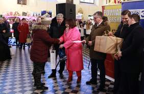 Pokaż zdjęcie: miejsce w którym rozdawane są nagrody laureatom to kościół. Na zdjęciu stoi dużo osób po środku osoby wręczają nagrody dla laureatów konkursu. W tle zamieszczono bilbordy sponsorów i organizatorów konkursu.