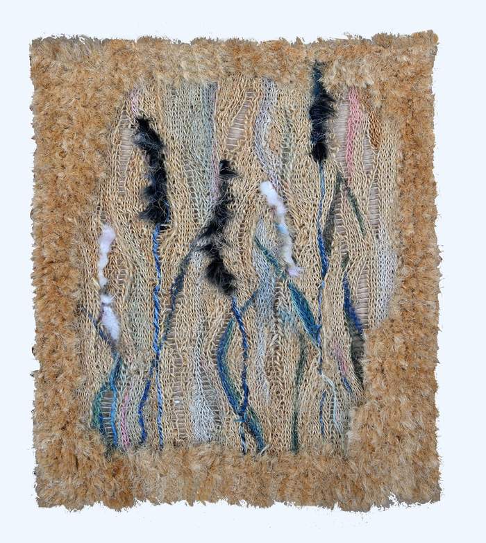 Pokaż zdjęcie: Ręcznie wykonana tkanina artystyczna w naturalnych odcieniach beżu, brązu i błękitu, z wyraźnie widoczną strukturą splotów. Praca ma nieregularne, falujące wzory z dodatkiem czarnych i białych włókien, które nadają jej dynamiczny charakter. Całość otoczona jest puszystą, beżową ramą z tekstylnego materiału, co podkreśla organiczny styl kompozycji.