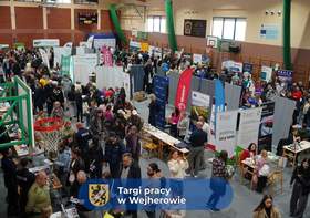 Hala sportowa wypełniona uczestnikami targów pracy w Wejherowie. Widoczne liczne stoiska wystawców i odwiedzający.
