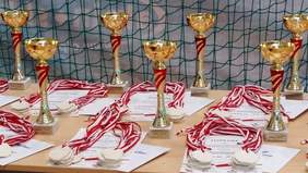 Pokaż zdjęcie: Nagrody dla zwycięzców – stół z pucharami i dyplomami