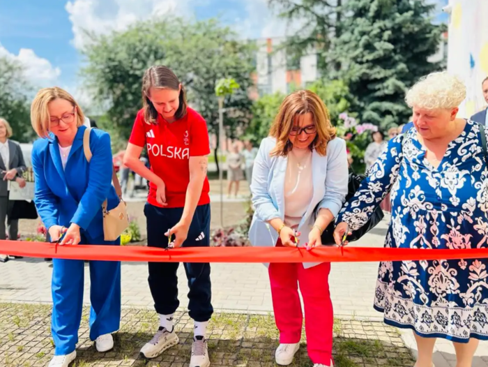 Pokaż zdjęcie: Czerwoną wstęgę przed boiskiem przecinają cztery kobiety.