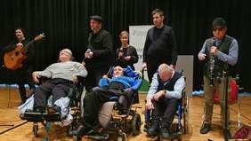 Pokaż zdjęcie: Występ Teatru EXIT - na scenie osoby z rożnymi niepełnosprawnościami, w tym osoby na wózkach i niewidome.